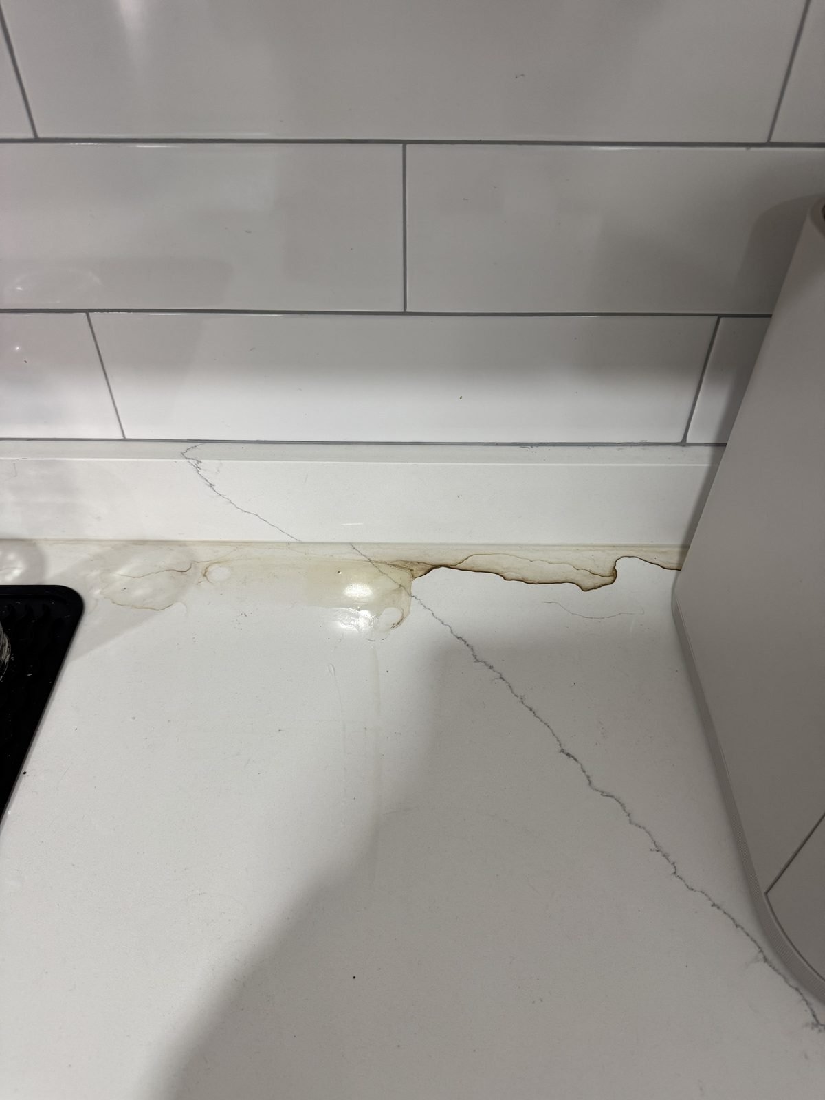 Kitchen counter before cleaning — dried spill along the backsplash